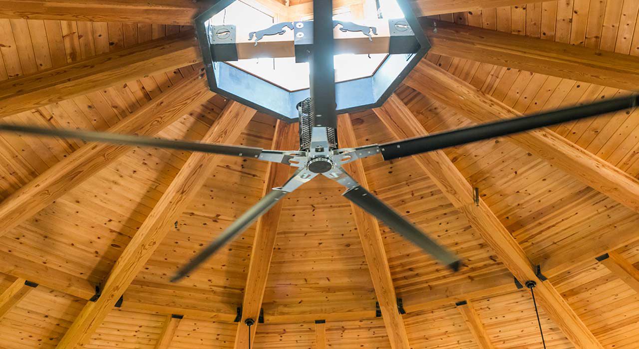 A black and silver fan on a wooden ceiling