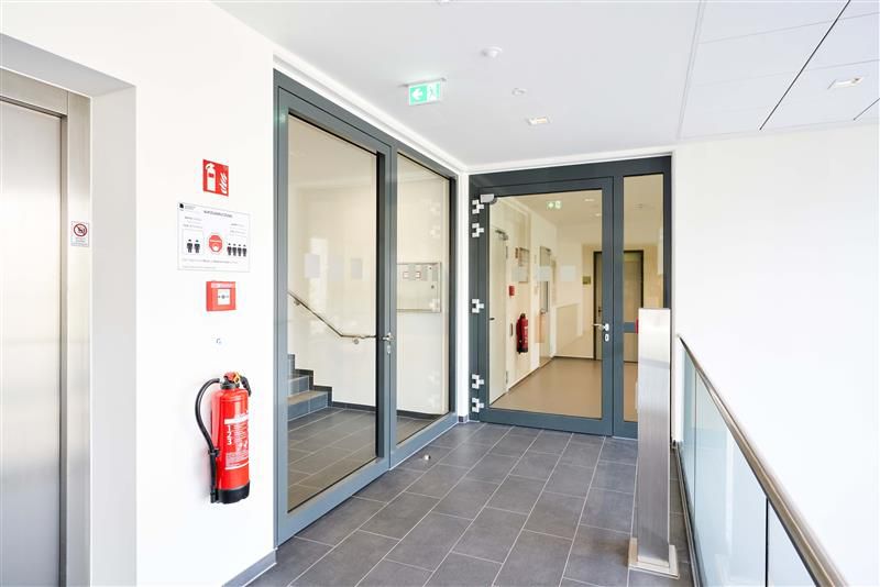 Treppenhaus mit Aufzug und zwei doppelflügeligen Rohrrahmentüren