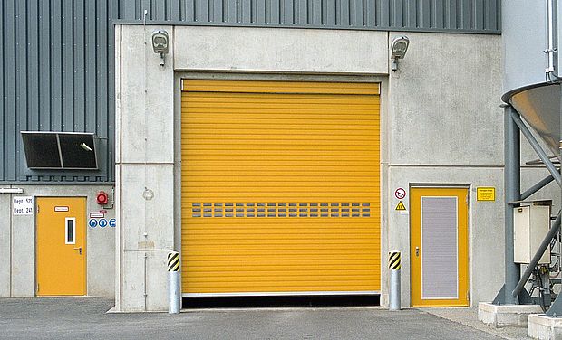 Gelbes Rolltor mit Verglasungslamellen und zwei gelben Nebentüren 