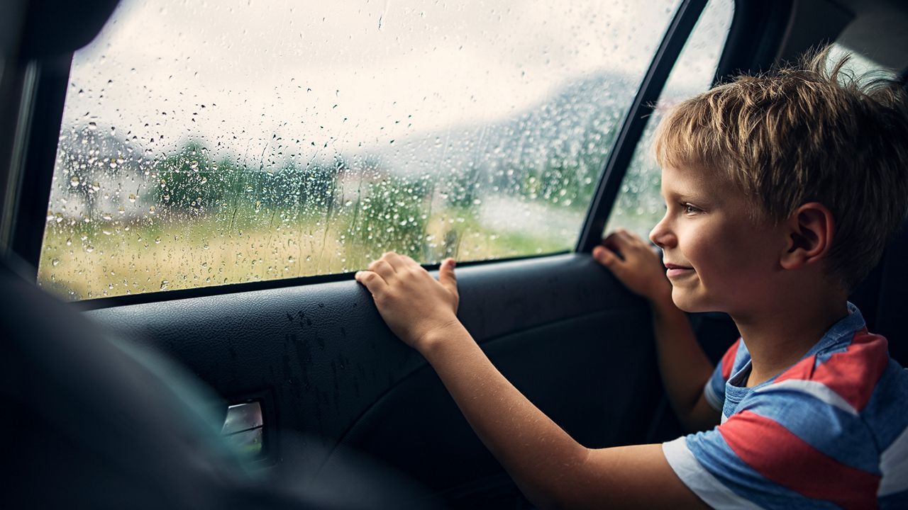 Pojke sitter i bilen och tittar ut på regnet.