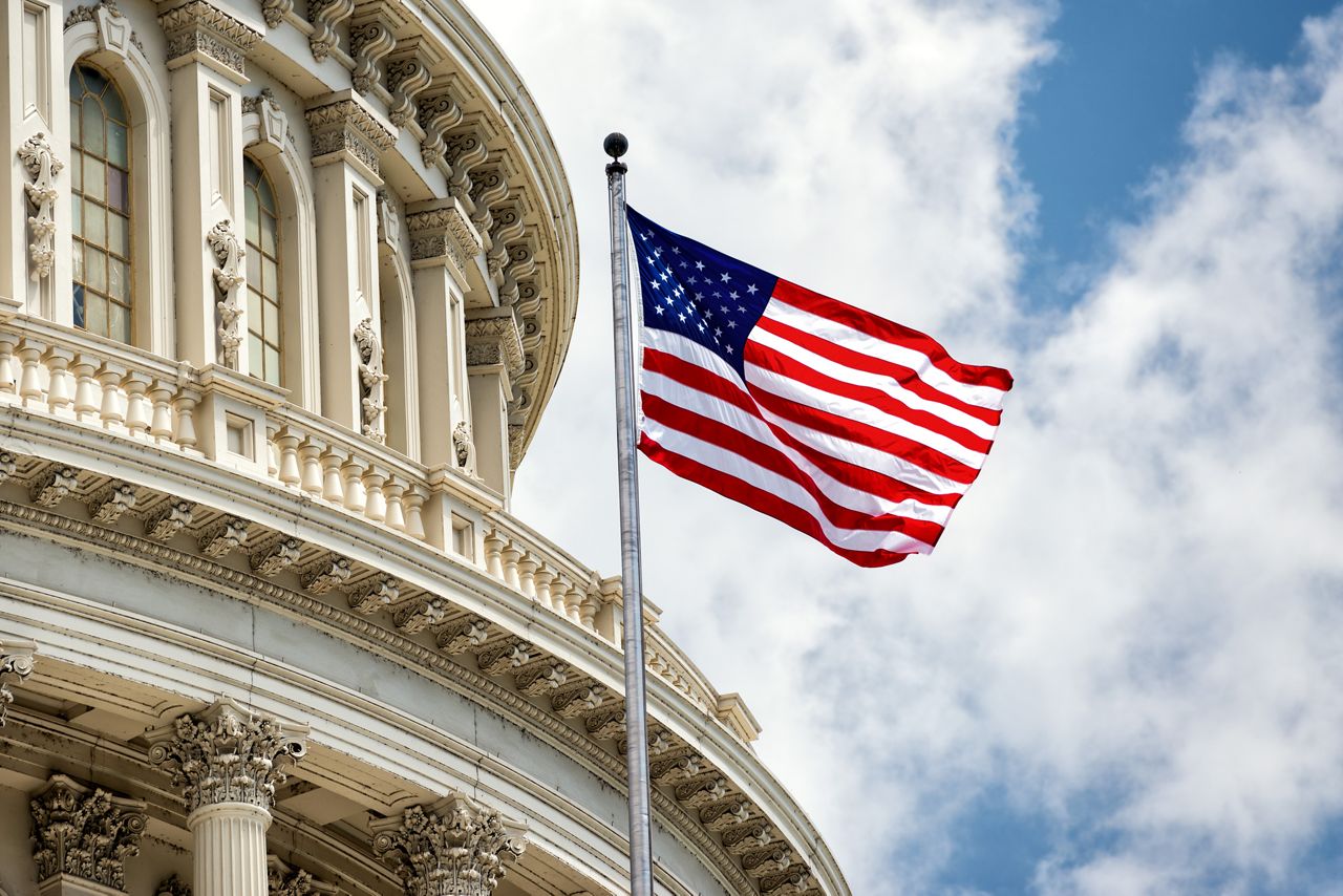 US flag flying in front of the Capitol building
