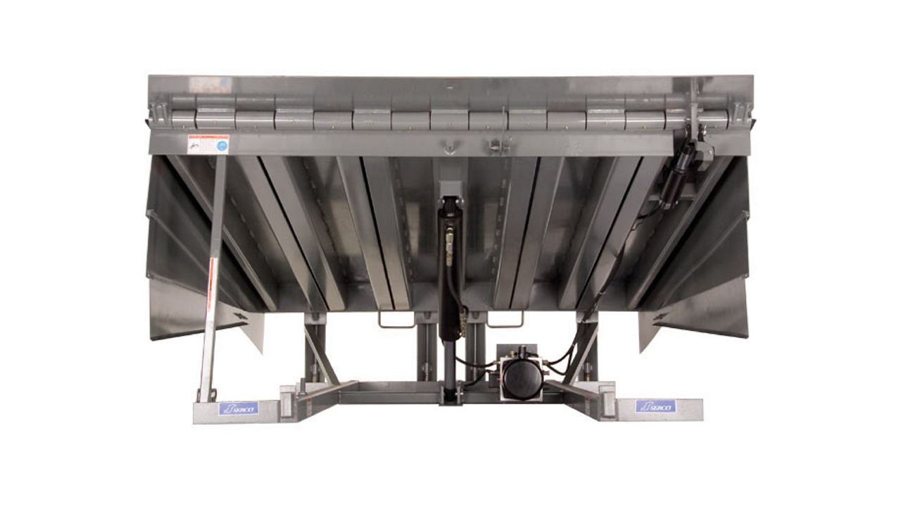 A silver hydraulic dock leveler with side panels.