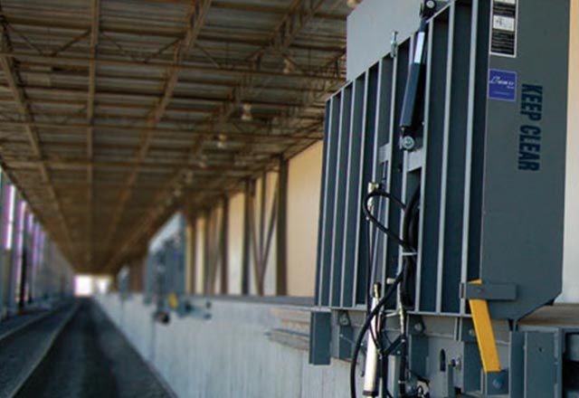 A rail mounted vertical storing dock leveler attached outside of a warehouse.