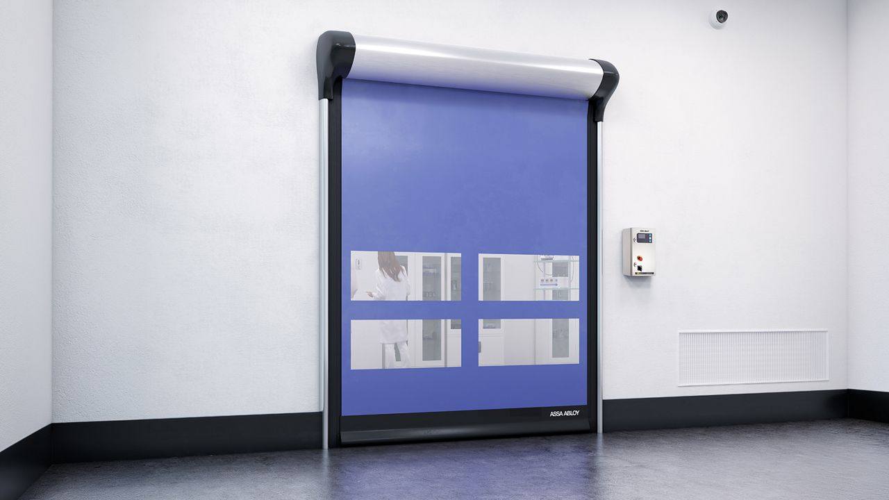 Porta Rápida para Sala Limpa ASSA ABLOY HS9130GAT, azul com janelas transparentes instalada em ambiente interno de laboratório ou área limpa.