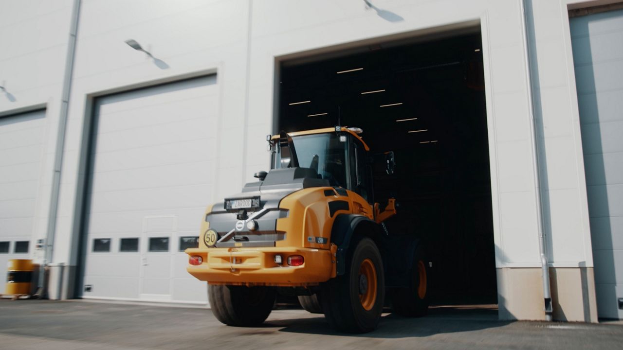 Tractor entering through an open industrial door in an industrial yard
