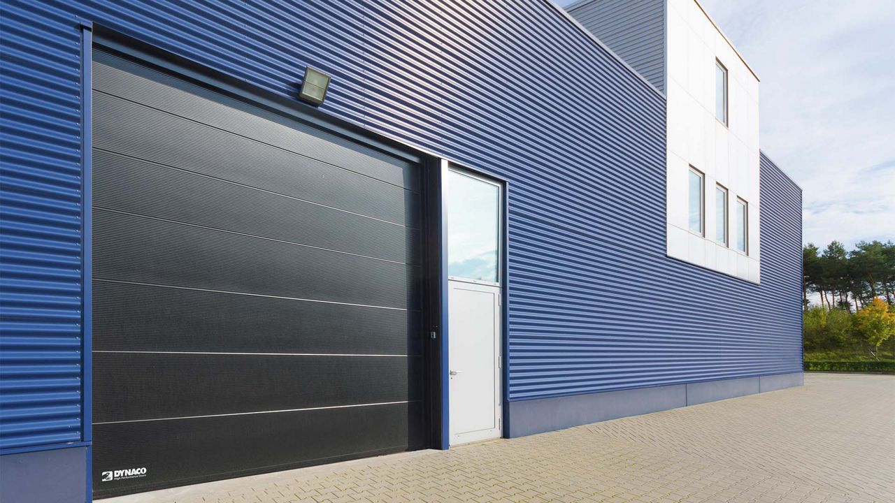 A black door outside a blue building.