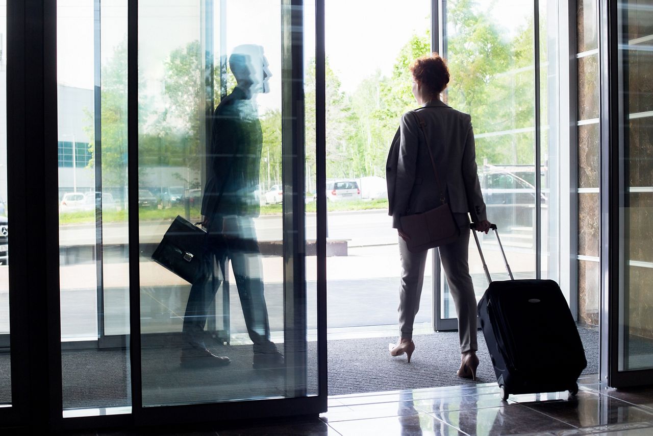 Woman exiting a hotel with luggage