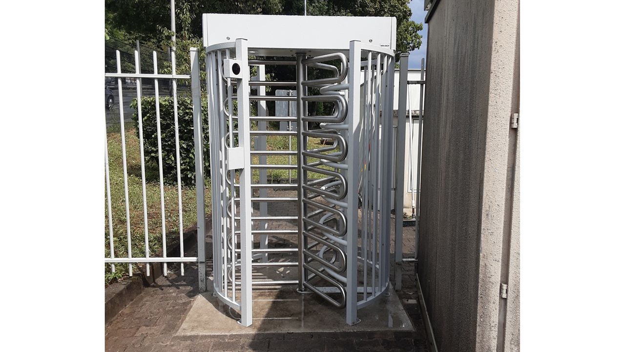 Hoog draaihekken bij de ingang van een bedrijfspand. Gebogen model type FT400, geplaatst in een buitenomgeving.