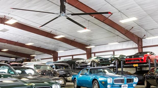 Image: An Industrial HVLS Fan hanging from a ceiling in a car lot.