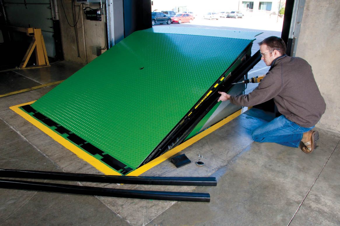  A man installing a green and black dock seal on a green dock leveler