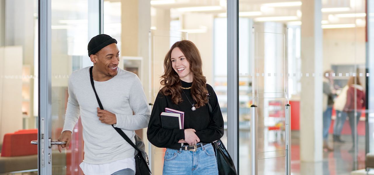 Two students walking out a campus building