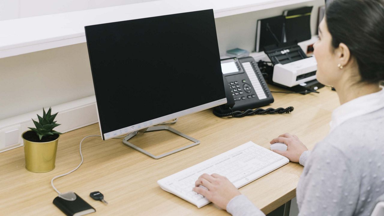 Kvinde sidder foran en computer ved skrivebord