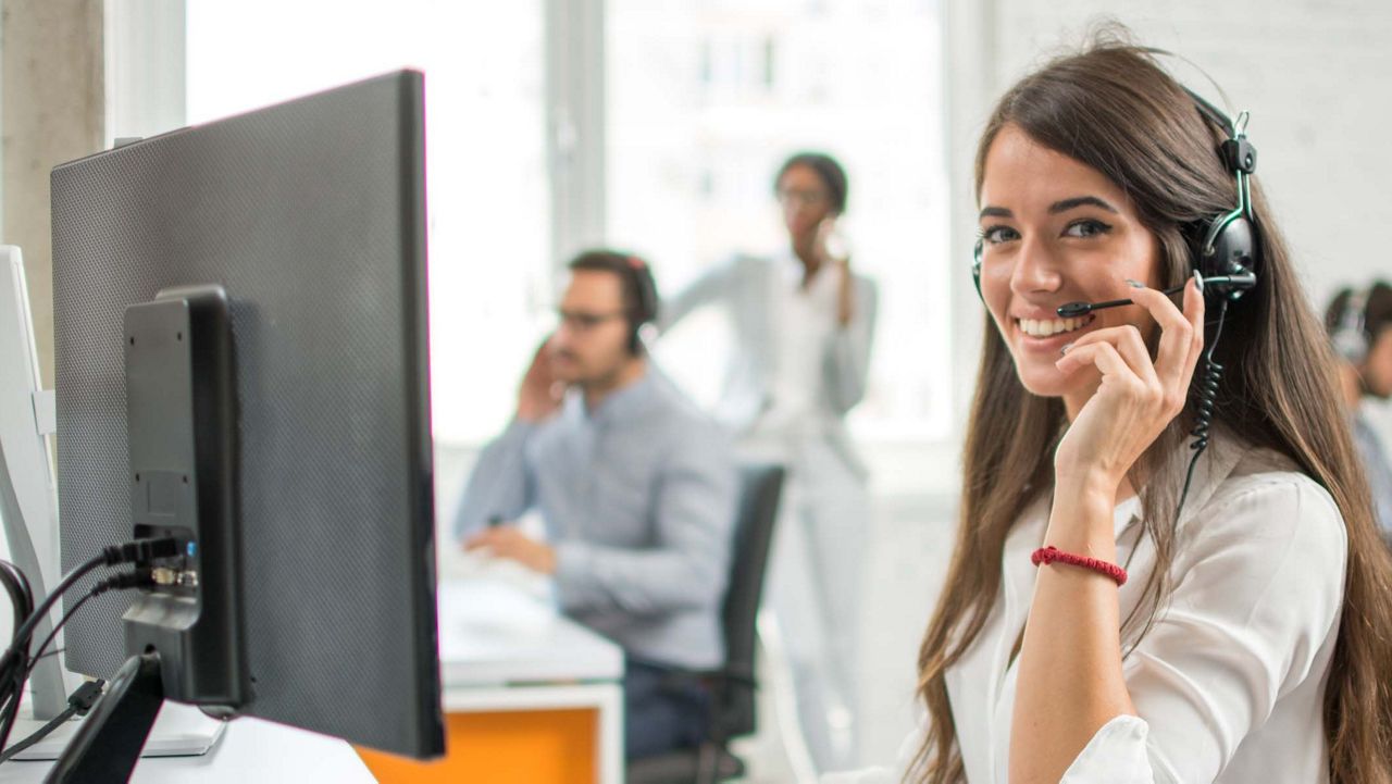 Woman sitting at computer with headset on head.