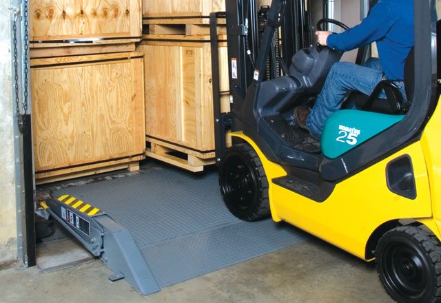 Image: The LH Loadhog Dock Bridge being driven over as a man uses a forklift to lift a pallate.