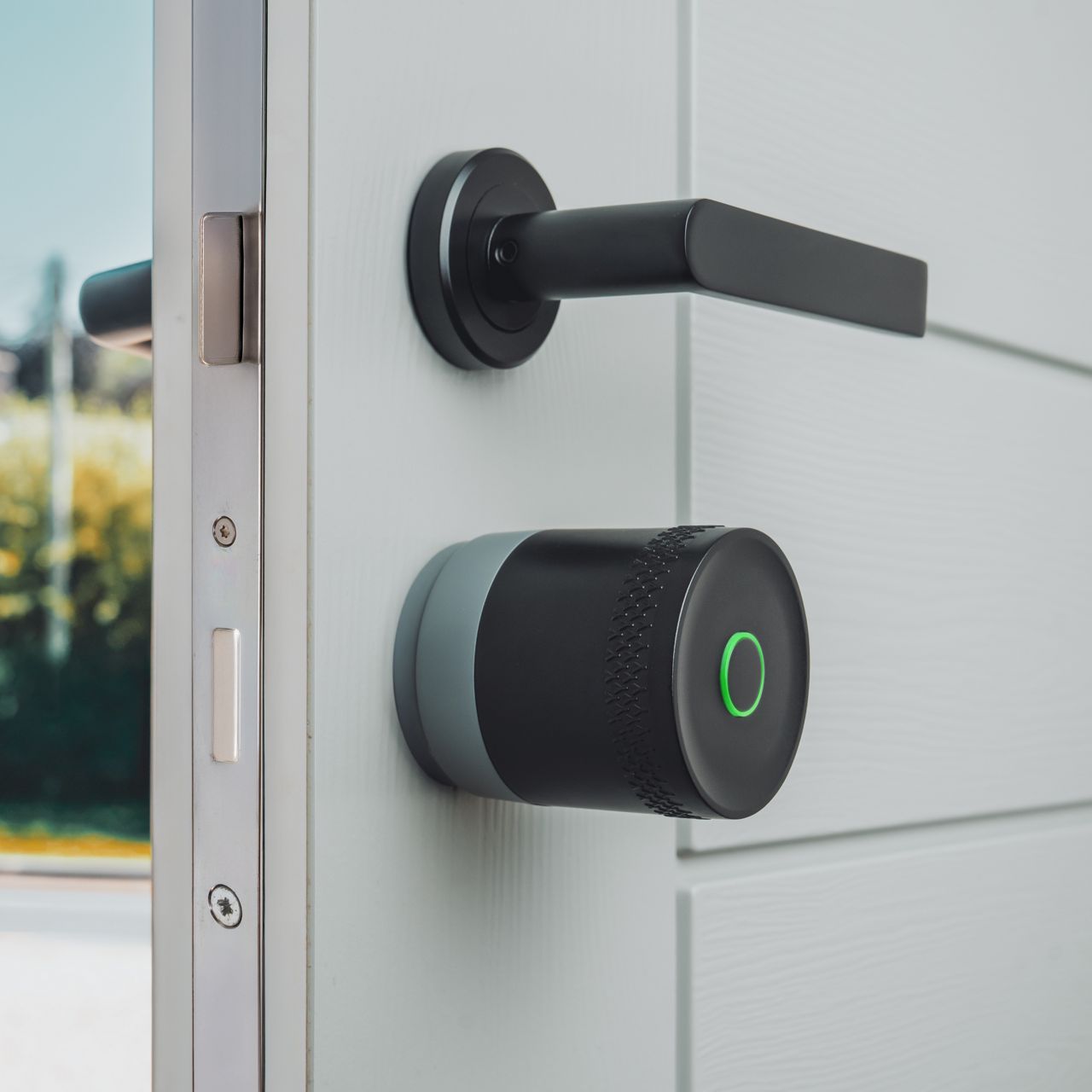 Image: Smart lock with green LED ring and curved metallic door handle on gray door