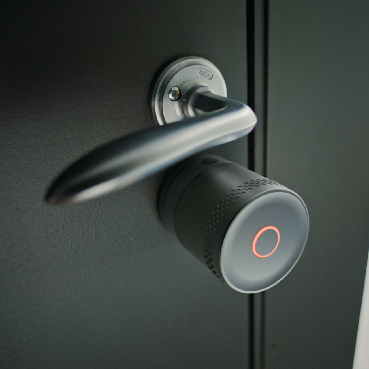 Image: Hands interacting with smart lock and metallic door handle on light gray textured door
