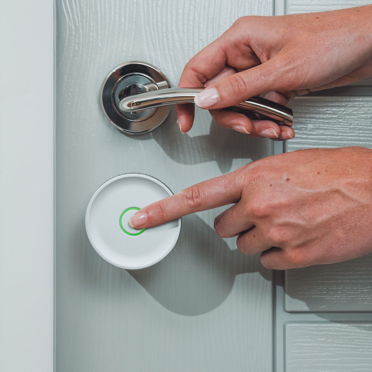 Image: Smart lock with green LED ring and curved metallic door handle on gray door