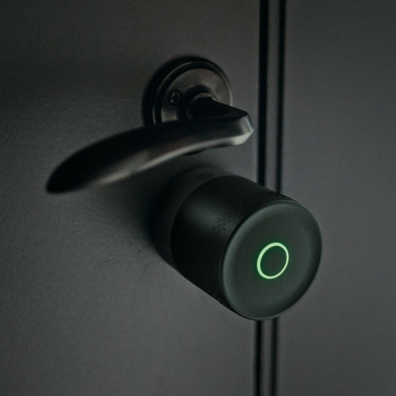 Image: Smart lock with glowing red LED ring and sleek metallic door handle on dark door