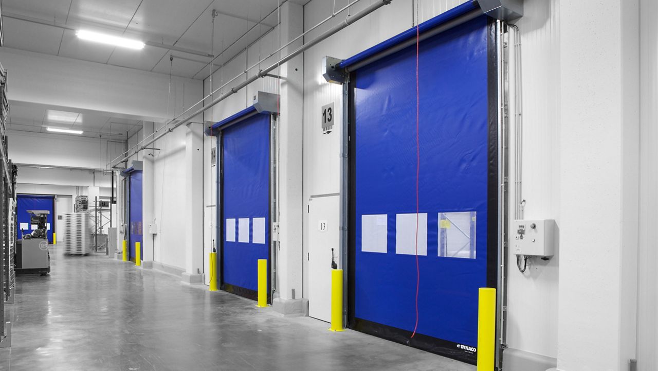 Een grijze gang met blauwe koude kamer deuren.