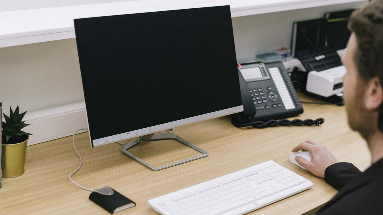 Man sidder ved skrivebord med computer foran sig