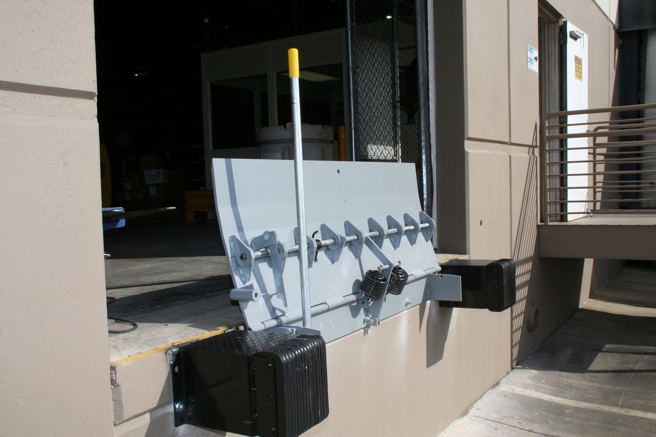 A silver edge of dock leveler attached outside of a warehouse.