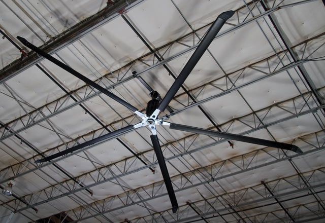 A black and silver fan on a white ceiling with metal rods