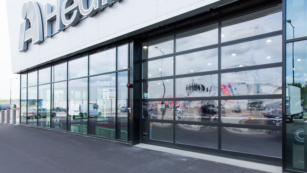 A glass door at a car dealers, where you can see the cars inside of the windows.