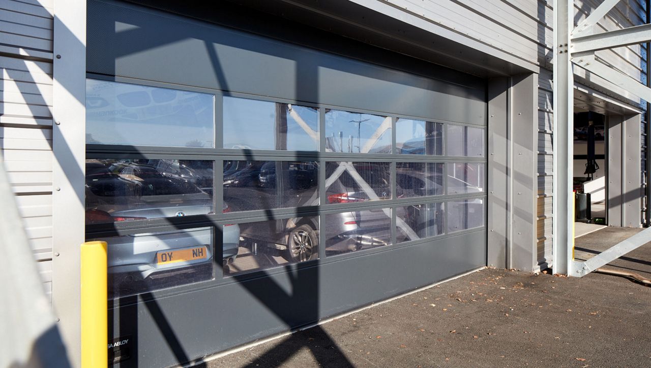 An external image of a Crawford OH1042F Overhead Sectional Door in a service bay at a BMW car dealership in the UK