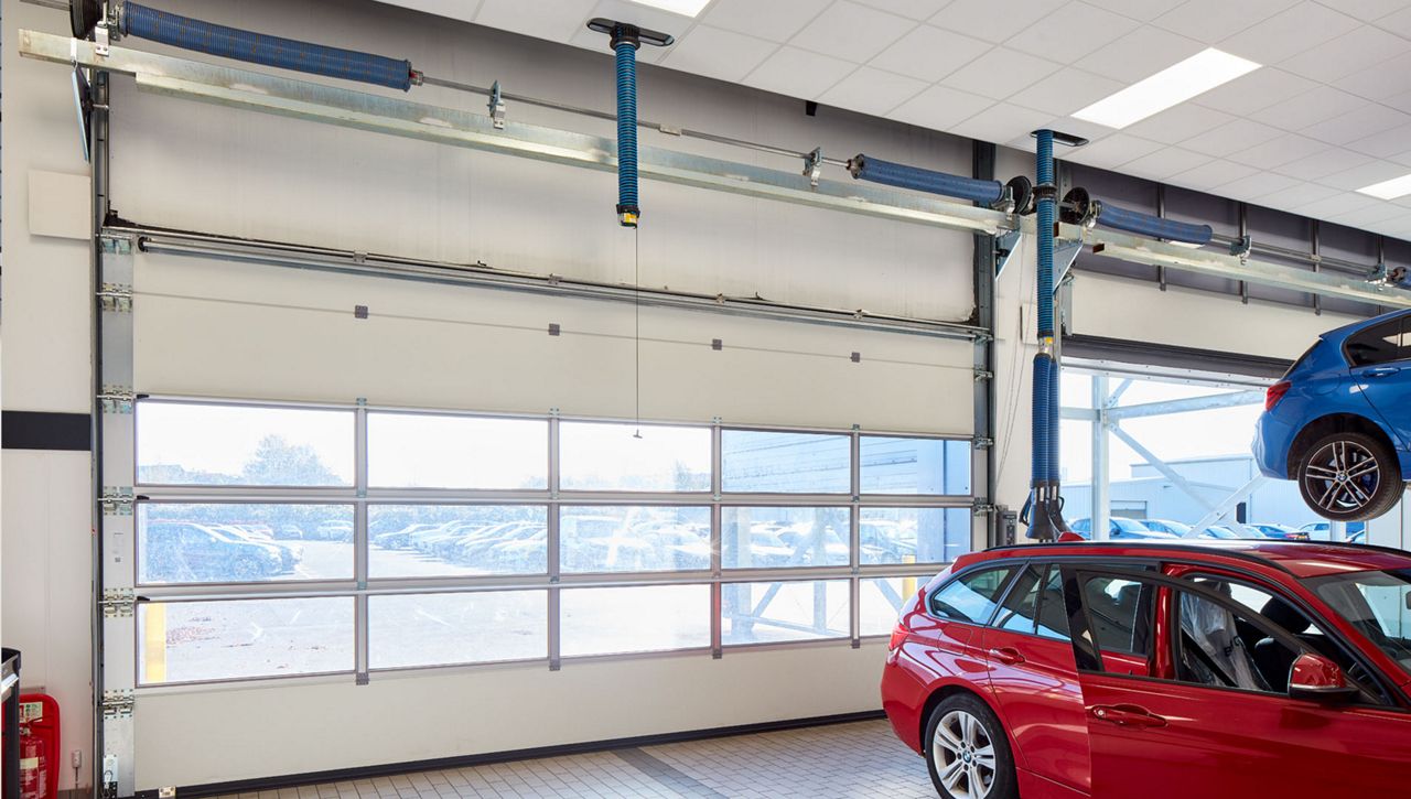 Image: An internal image of a Crawford OH1042F Overhead Sectional Door in a service bay at a BMW car dealership in the UK