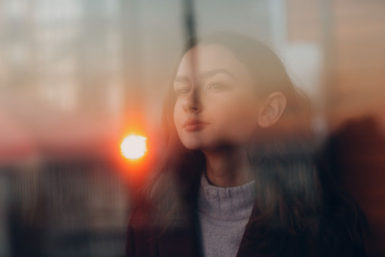 A young girl portrait behind window glass