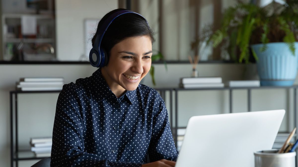 Kvinde sidder foran sin computer og smiler