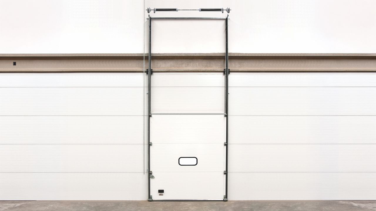 Image: Porta Seccional Industrial Inovadoor Série 500, branca com porta de acesso integrada e painel seccionado isolado
