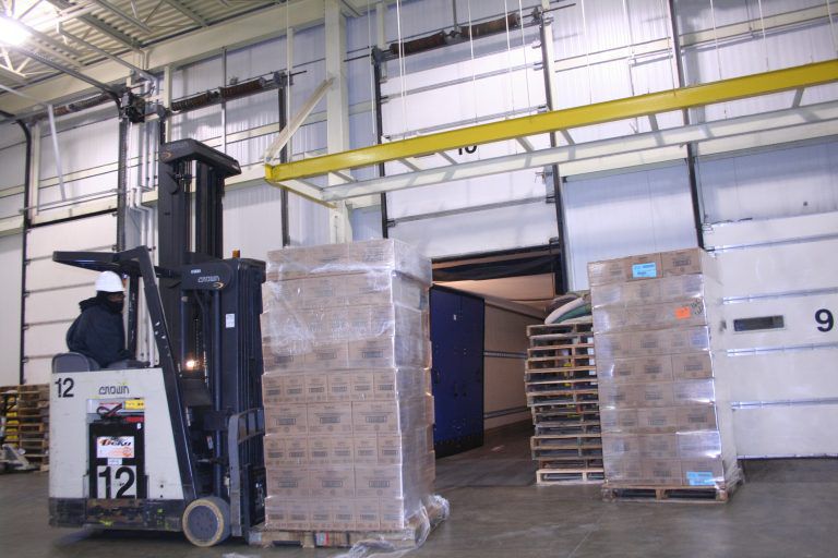 A small forklift picking up a stack of boxes in a warehouse