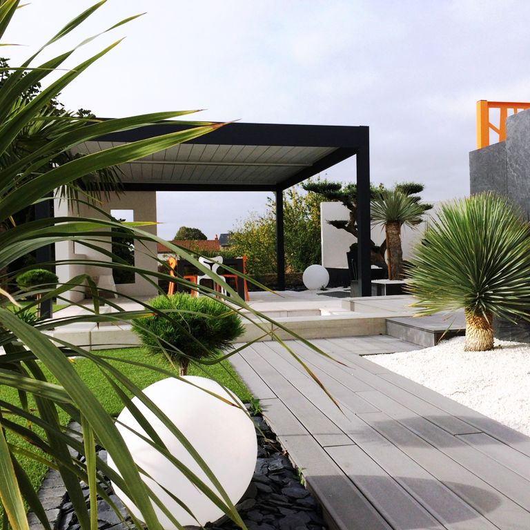 Pergola bioclimatique grise au fond d'un jardin