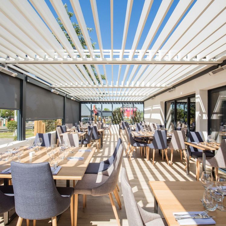 Pergola bioclimatique blanche couvrant une terrasse de restaurant