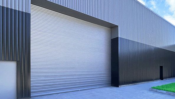 Batiment industriel gris avec un rideau métallique fermé.