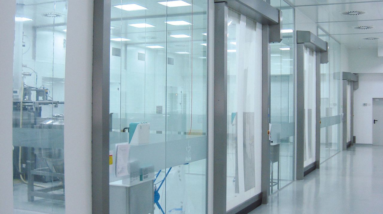 A hospital hallway with glass walls and cleanroom doors.