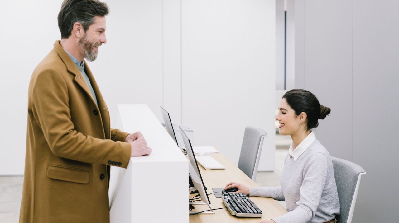 Mand står ved reception og taler med receptionisten