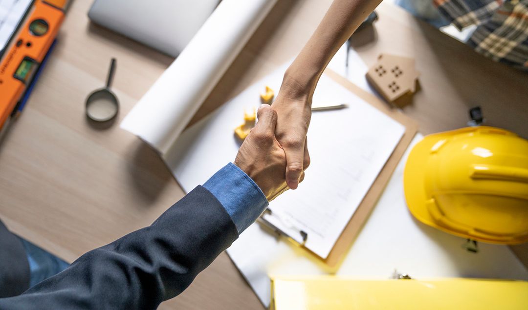 Two people shaking hands over a table.