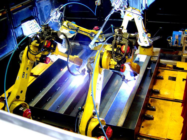 A yellow robot welding metal