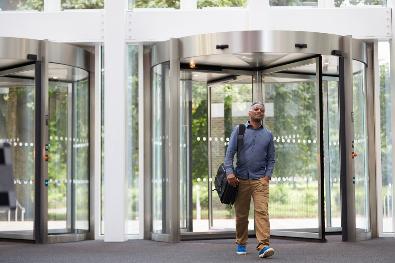Man entering a building lobby through a rotating door