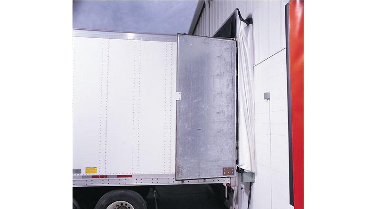 A white truck backing into a door with a dock shelter.