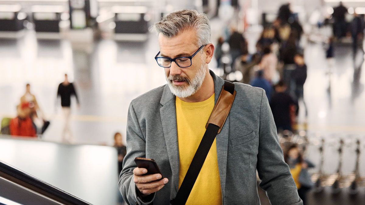 A man on a escalator holding a smart-phone in a airport