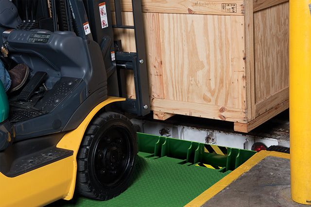 A forklift picking up a box while being held in place by a safety barrier lip