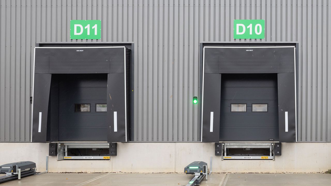 Image: Abrigo de Doca Inovadoor 202, instalado em docas de carregamento de centro logístico, com cortinas de vedação frontal em lona resistente e faixas refletivas laterais de alta visibilidade