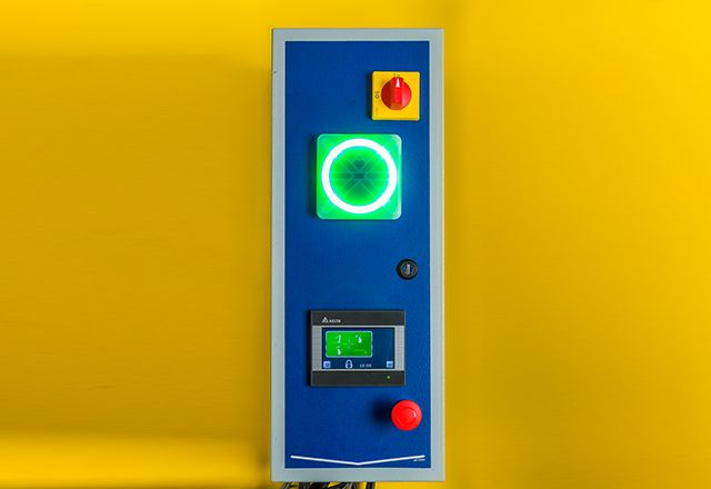The Master Control Panel (a blue prism with a red button and lit up green circle) on a yellow background