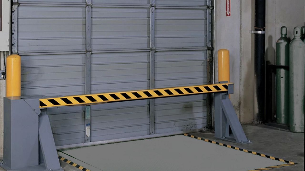 A black and yellow painted metal rectangular gate that is supported by a gray base