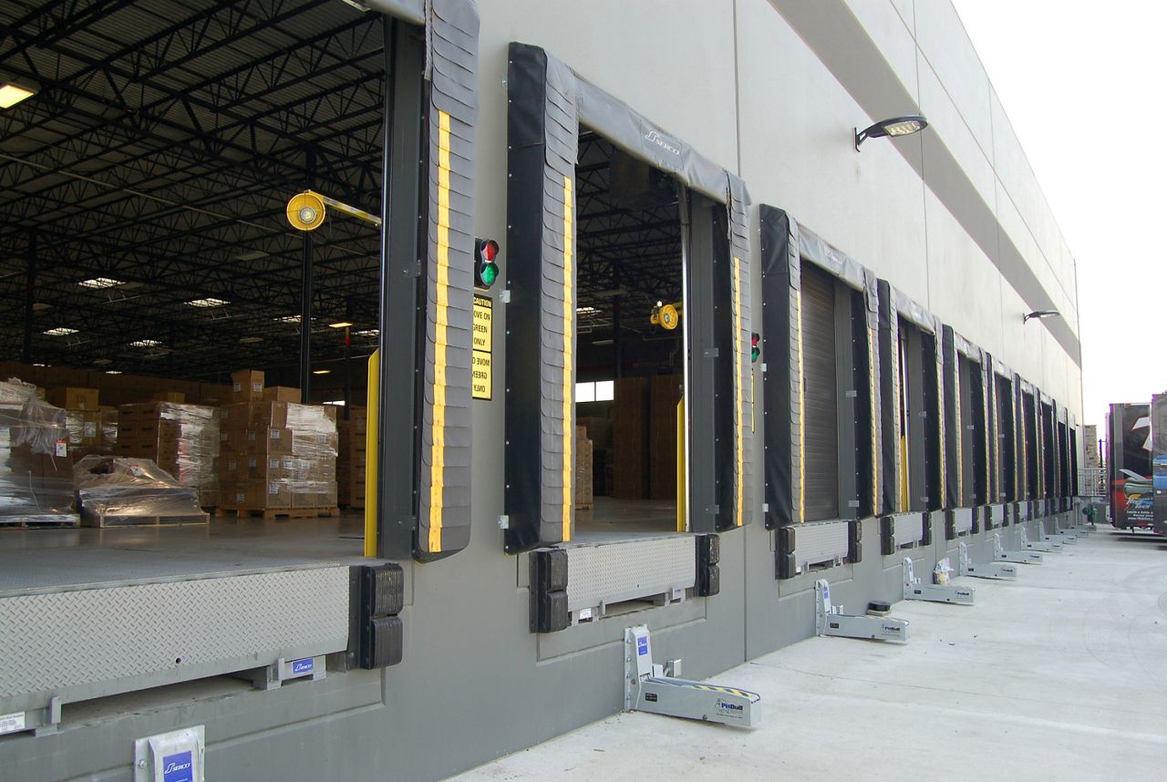 A line of doors with dock seals on the outside of a warehouse.