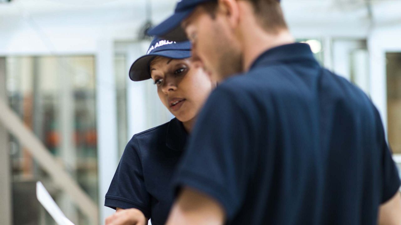 Une femme portant une casquette bleue montre un document à une personne à côté d'elle