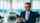 Car salesman using smartphone in showroom
